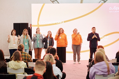 Шесть модераторов Академии развития гражданского общества «Добрино», в том числе две студентки ЮГУ, машут руками участникам Всероссийского форума, которые сидят перед ними