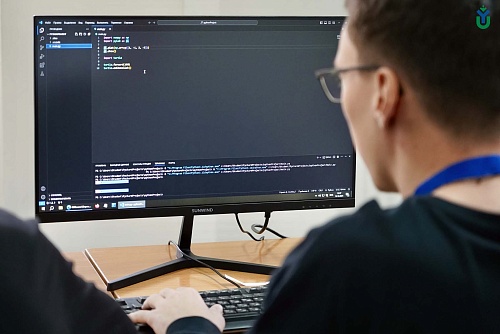 На фото студент ЮГУ сидит спиной к камере, перед ним экран монитора, на котором отображается код на языке Python в интегрированной среде разработки PyCharm