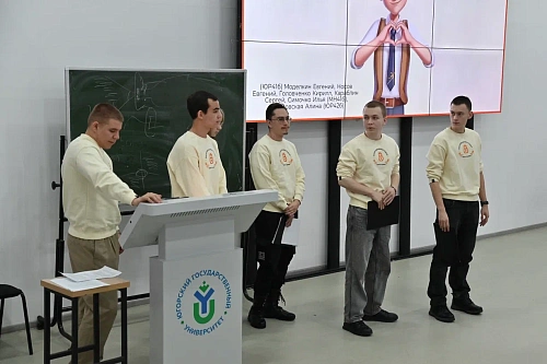 На изображении пять молодых людей в светлых кофтах с логотипом, стоящих перед аудиторией. Логотип на кофтах представляет собой стилизованную восьмерку, внутри которой написано 