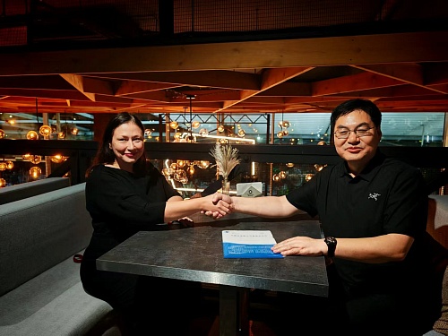 Руководитель Карбон Дата Центра Ирина Иванова в Сочи передаёт подписанный меморандум о взаимопонимании представителю Института физики атмосферы Китайской академии наук, они сидят за столом и пожимают руки