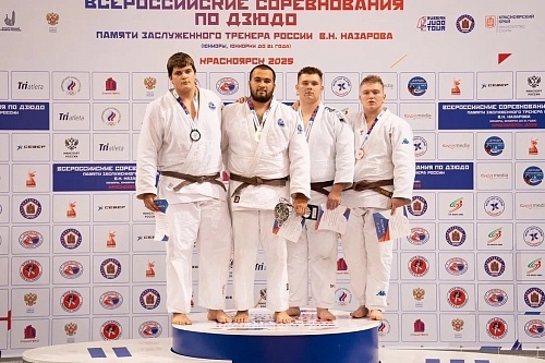 Четыре спортсмена в кимоно стоят на пьедестале с медалями и грамотами на Всероссийских соревнованиях по дзюдо 