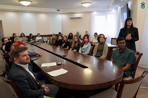 Студенты ЮГУ сидят за большим овальным столом в кабинете ЮГУ, где проходит видеоконференцсвязь с Международным университетом Даффодил в Бангладеш