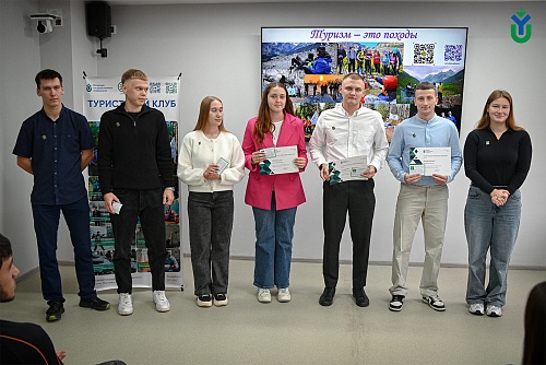 Лучшие студенты-туристы ЮГУ стоят с благодарностями и нагрудными знаками на торжественном мероприятии по случаю Дня туризма